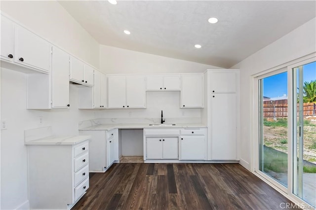 kitchen featuring white cabinets, vaulted ceiling, dark wood-type flooring, and sink