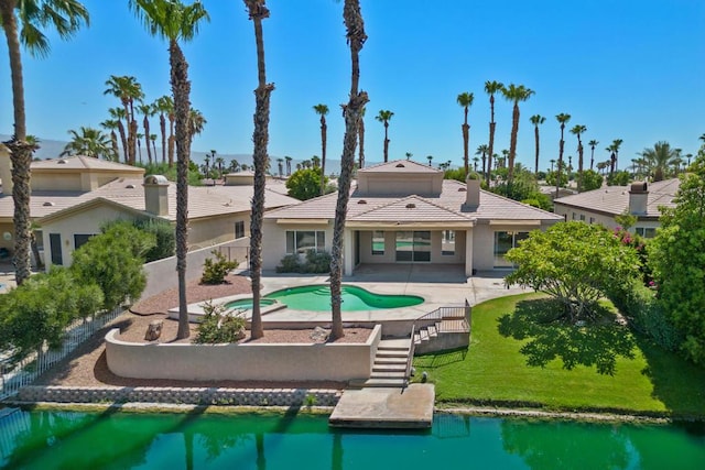 back of house featuring a water view, a yard, and a patio