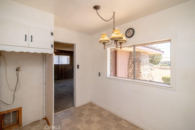 unfurnished dining area with light floors, baseboards, a chandelier, and visible vents