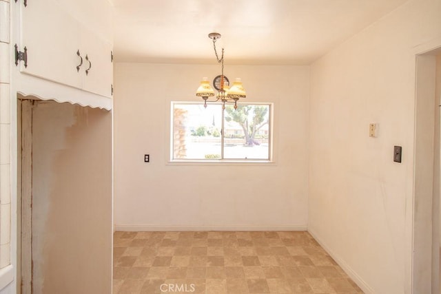 unfurnished dining area with baseboards and a chandelier