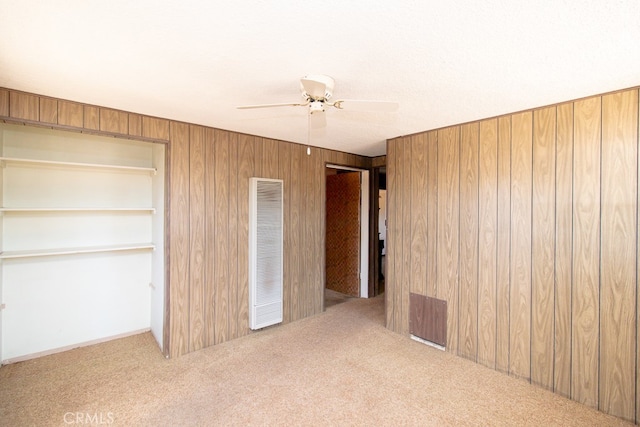 unfurnished bedroom with ceiling fan, wood walls, and carpet flooring