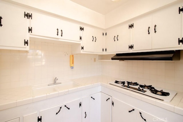 kitchen with white cabinetry, white gas stovetop, tile countertops, and under cabinet range hood