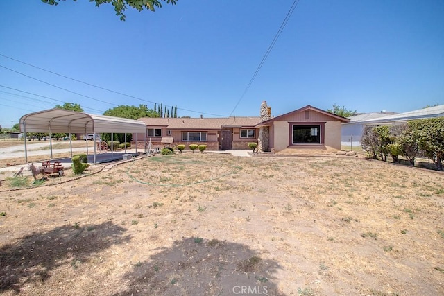 ranch-style house featuring a chimney and a detached carport