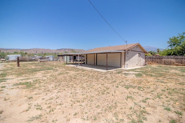 rear view of property with an outbuilding, an exterior structure, a mountain view, and a detached garage