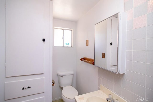 half bathroom featuring toilet, backsplash, and vanity