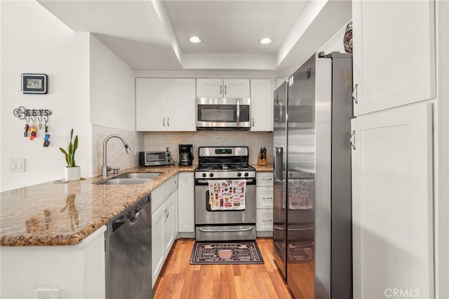 kitchen featuring light hardwood / wood-style floors, appliances with stainless steel finishes, white cabinets, and sink