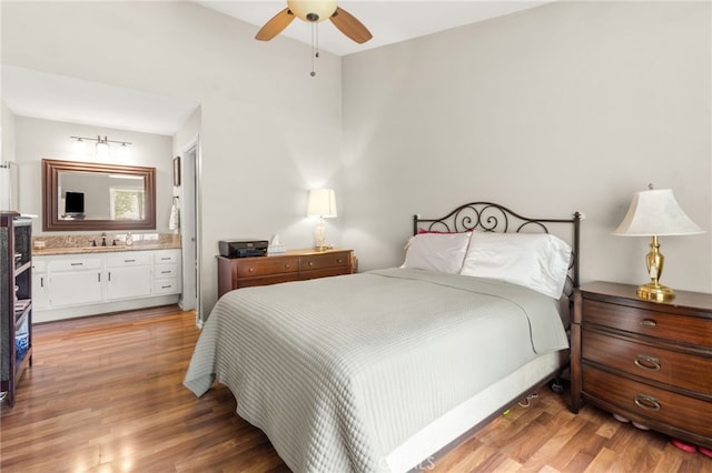 bedroom featuring light hardwood / wood-style floors, connected bathroom, sink, and ceiling fan