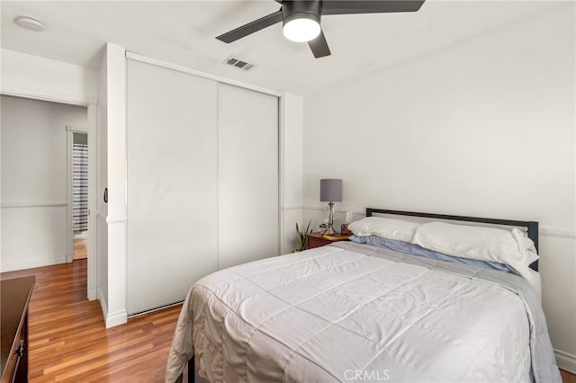 bedroom with a closet, hardwood / wood-style floors, and ceiling fan