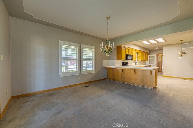 kitchen with a kitchen breakfast bar, kitchen peninsula, pendant lighting, and light colored carpet