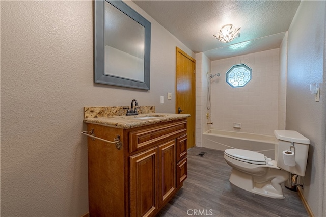 full bathroom with vanity, toilet, tiled shower / bath combo, a textured ceiling, and hardwood / wood-style floors