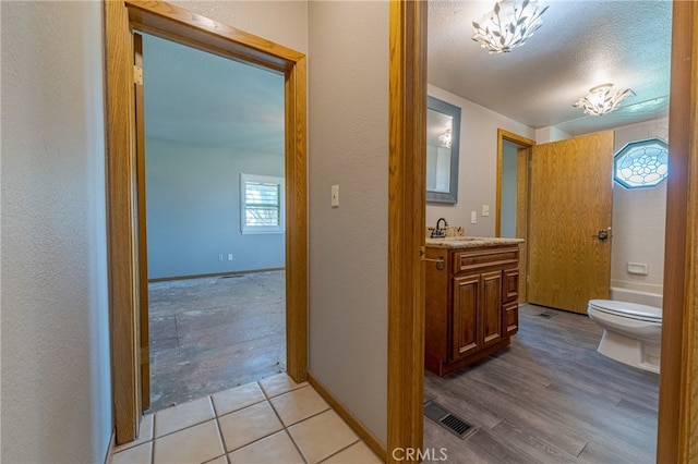 bathroom with a textured ceiling, vanity, toilet, and hardwood / wood-style flooring