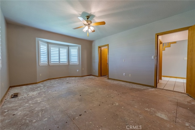 empty room with ceiling fan and a textured ceiling