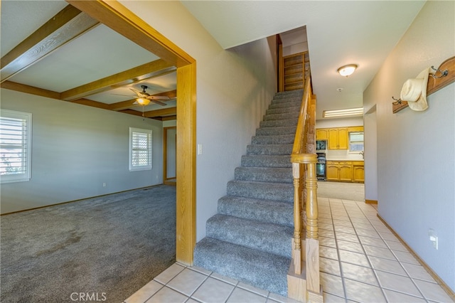 stairway featuring beamed ceiling, ceiling fan, and tile patterned floors