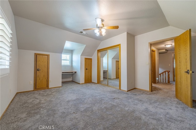 interior space featuring a textured ceiling, lofted ceiling, ceiling fan, and light colored carpet