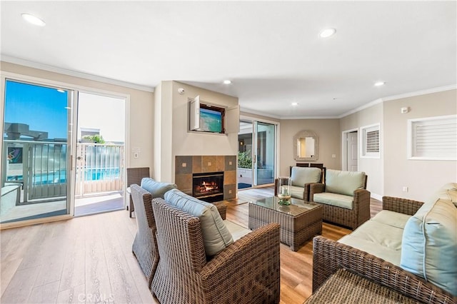 living room featuring light wood-type flooring, a fireplace, ornamental molding, and recessed lighting