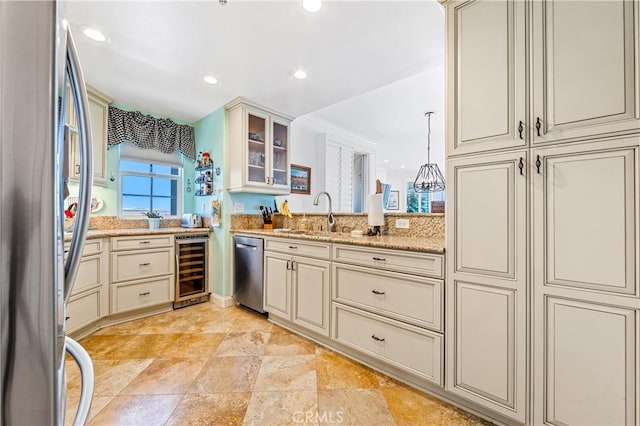 kitchen with beverage cooler, a sink, appliances with stainless steel finishes, cream cabinetry, and glass insert cabinets