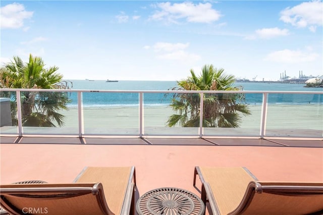 balcony with a water view and a view of the beach