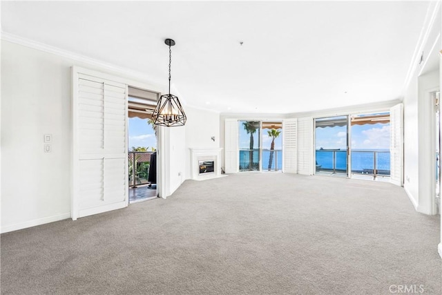 unfurnished living room featuring carpet, ornamental molding, a water view, and a fireplace with flush hearth