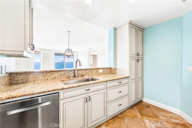 kitchen with hanging light fixtures, stainless steel dishwasher, a sink, light stone countertops, and baseboards