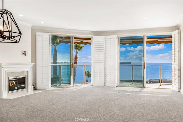 unfurnished living room with carpet floors, a water view, a fireplace, and crown molding