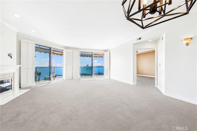 unfurnished living room with carpet, visible vents, a water view, a premium fireplace, and ornamental molding