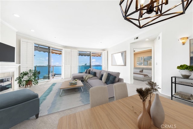 living room with a water view, visible vents, ornamental molding, and a tiled fireplace