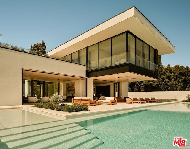 rear view of house with outdoor lounge area, a sunroom, a fenced in pool, and a patio area