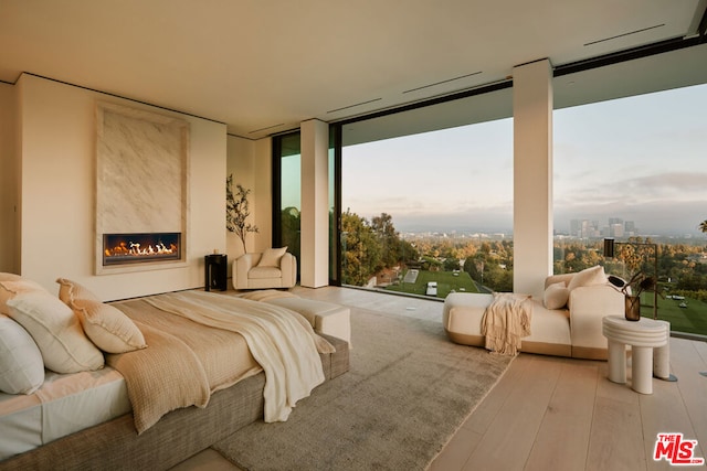 bedroom with light hardwood / wood-style flooring, floor to ceiling windows, and a fireplace