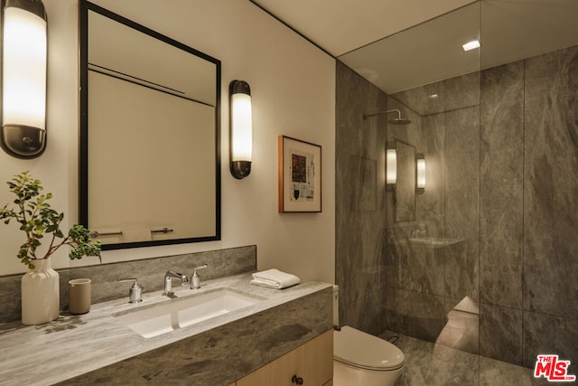 bathroom with tiled shower, vanity, and toilet