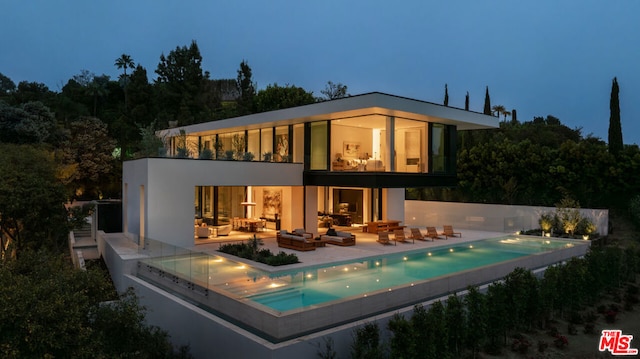 rear view of property with a patio and a fenced in pool