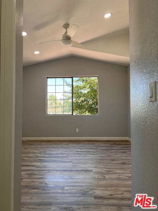 empty room featuring lofted ceiling, hardwood / wood-style floors, and ceiling fan