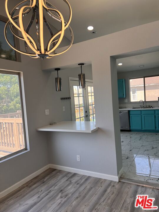 interior space with sink, a notable chandelier, light hardwood / wood-style floors, and french doors