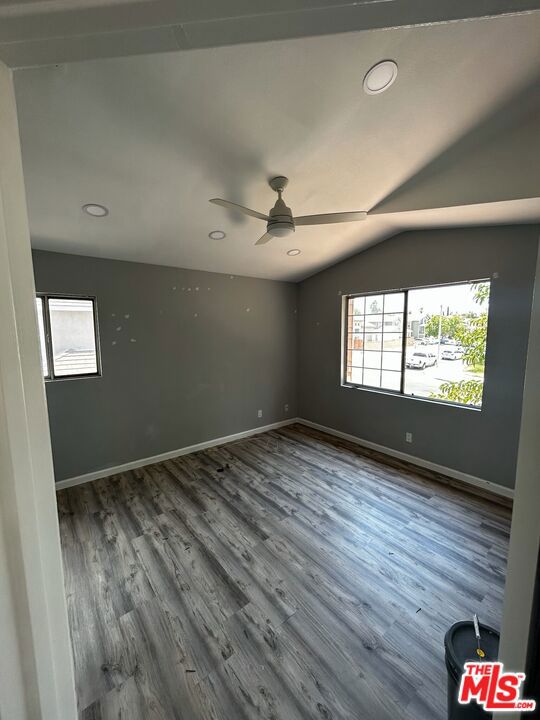 spare room with ceiling fan, a healthy amount of sunlight, wood-type flooring, and lofted ceiling