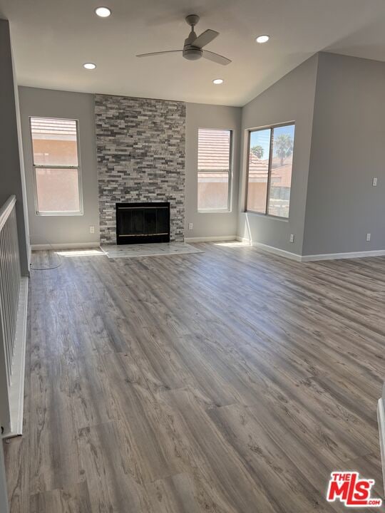 unfurnished living room featuring ceiling fan, vaulted ceiling, hardwood / wood-style floors, and a fireplace