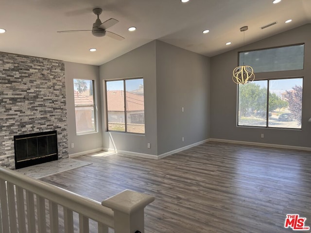 unfurnished living room featuring ceiling fan, lofted ceiling, dark hardwood / wood-style floors, and a stone fireplace