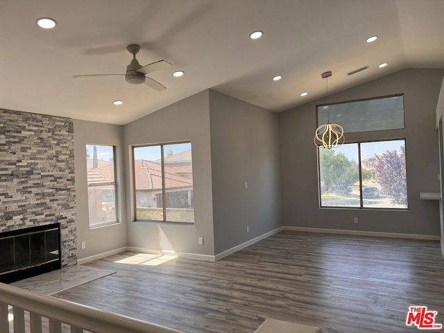 unfurnished living room featuring a stone fireplace, dark wood-type flooring, lofted ceiling, and ceiling fan