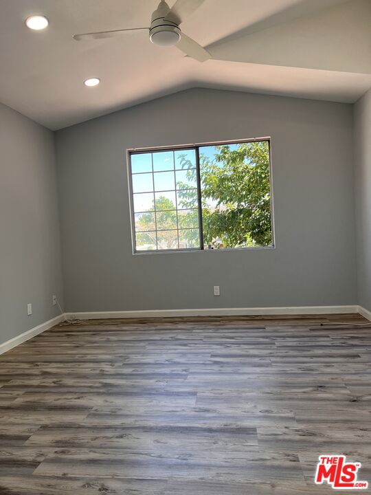 unfurnished room featuring lofted ceiling, dark wood-type flooring, and ceiling fan