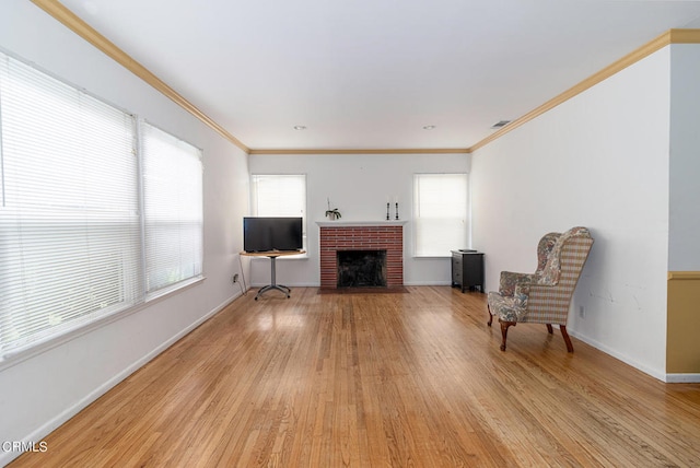 living area with a fireplace, light wood-type flooring, a wealth of natural light, and ornamental molding