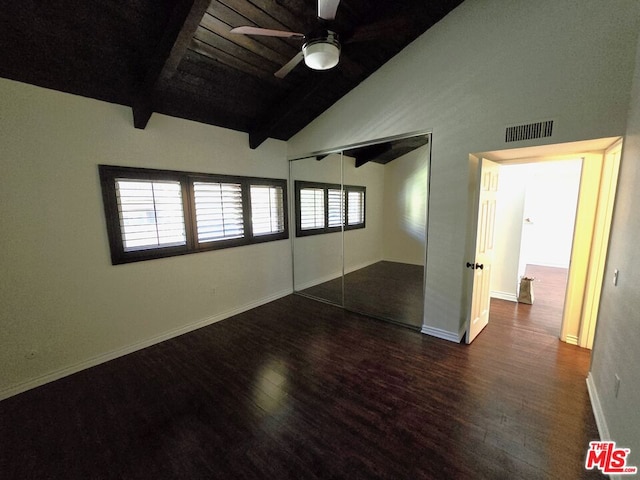 unfurnished bedroom with lofted ceiling with beams, dark wood-type flooring, multiple windows, and ceiling fan