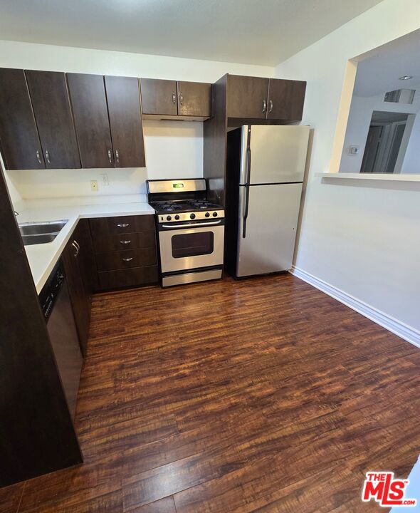 kitchen featuring dark brown cabinetry, appliances with stainless steel finishes, and dark hardwood / wood-style flooring