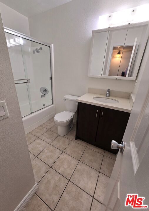 full bathroom with enclosed tub / shower combo, vanity, toilet, and tile patterned floors