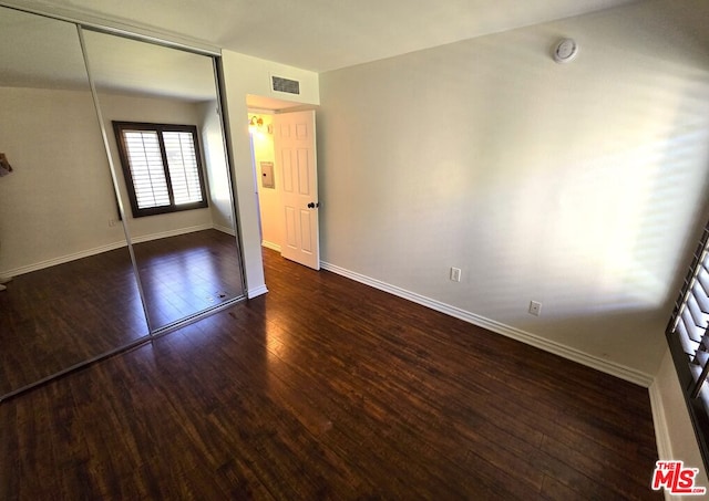 unfurnished bedroom with a closet and dark hardwood / wood-style flooring