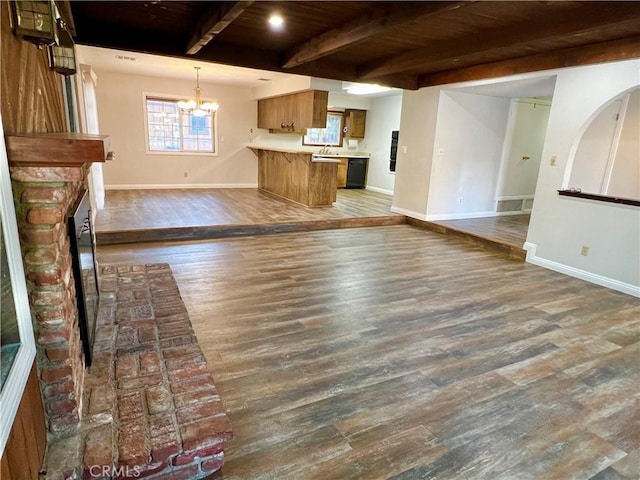 unfurnished living room featuring beam ceiling, sink, wooden ceiling, dark wood-type flooring, and a notable chandelier