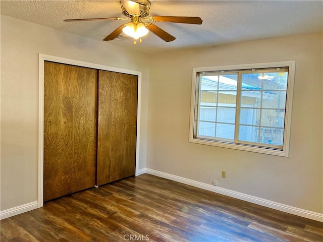 unfurnished bedroom featuring ceiling fan, a closet, dark wood-type flooring, and a textured ceiling