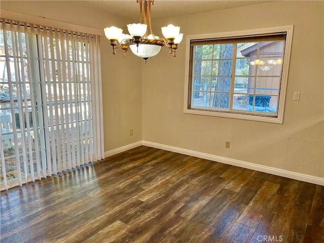 unfurnished dining area with dark hardwood / wood-style flooring, a textured ceiling, and a chandelier