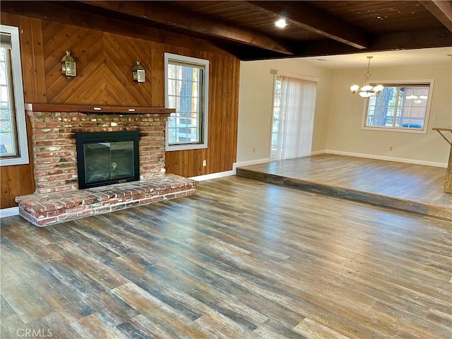 unfurnished living room featuring a wealth of natural light, wood-type flooring, and wooden walls