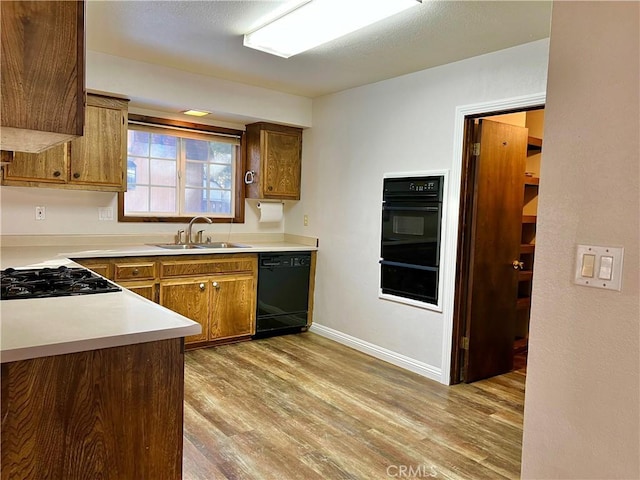 kitchen featuring black appliances, light hardwood / wood-style floors, and sink