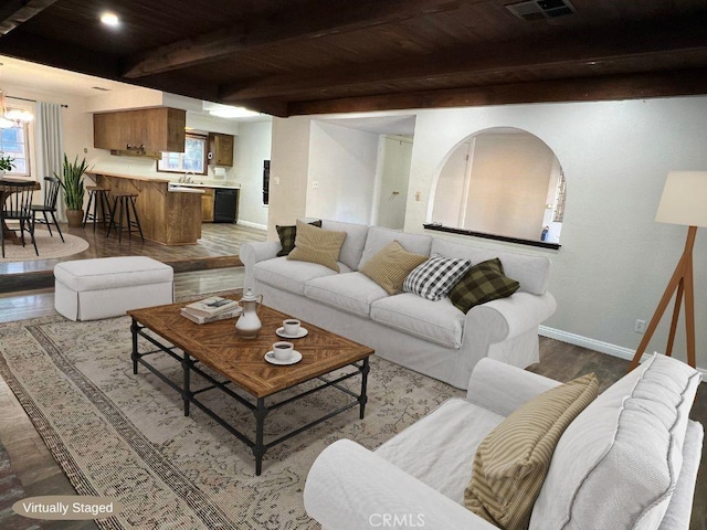 living room featuring beamed ceiling, hardwood / wood-style floors, an inviting chandelier, and wooden ceiling