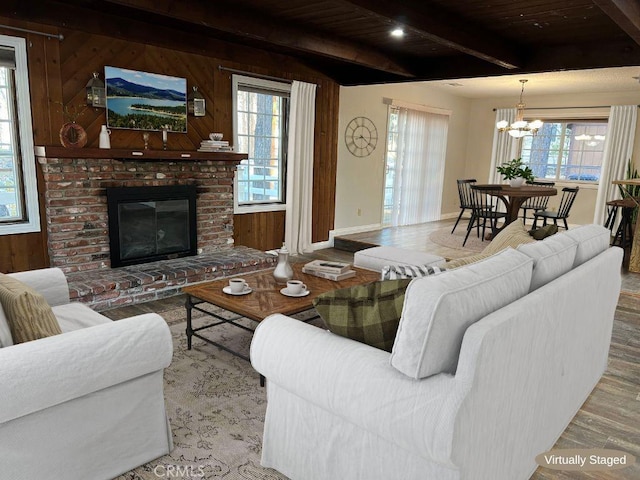 living room featuring beam ceiling, hardwood / wood-style flooring, a brick fireplace, and a wealth of natural light