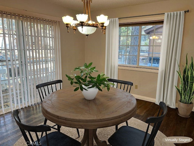 dining room featuring dark hardwood / wood-style flooring, a textured ceiling, and an inviting chandelier